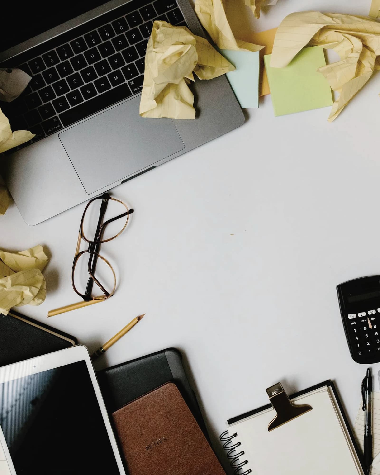 Mesa saturada de papeles, notas y dispositivos para representar caos operativo y retrabajo con Excel